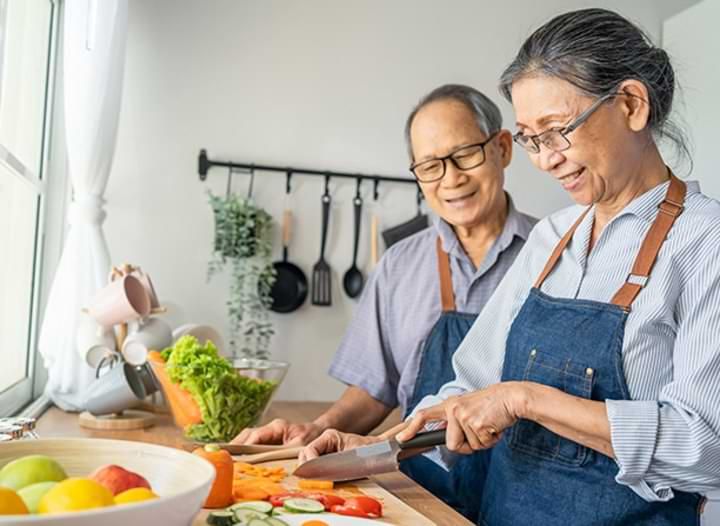 Older Asian couple preparing a meal together.